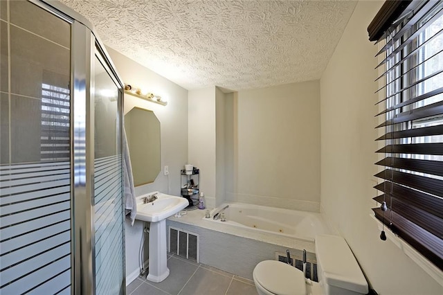 bathroom featuring tile patterned flooring, visible vents, a textured ceiling, and a whirlpool tub