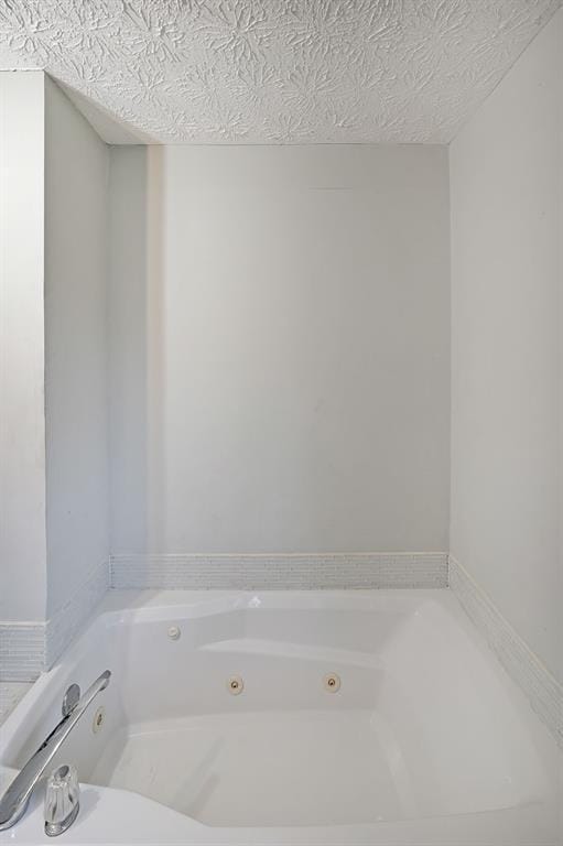 bathroom with a textured ceiling and a jetted tub