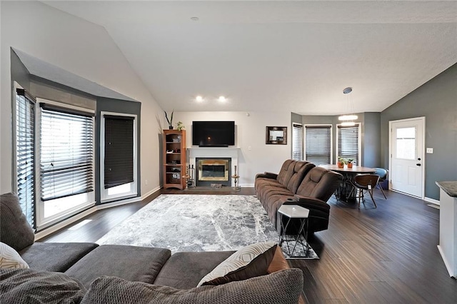 living area featuring lofted ceiling, a fireplace with flush hearth, dark wood-style floors, and baseboards