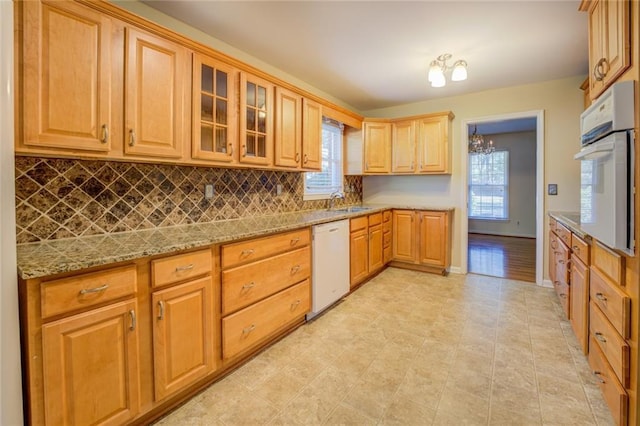 kitchen with tasteful backsplash, light stone countertops, plenty of natural light, and white appliances