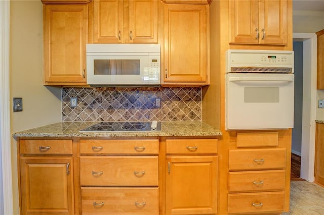 kitchen featuring light stone counters, white appliances, light tile patterned floors, and tasteful backsplash