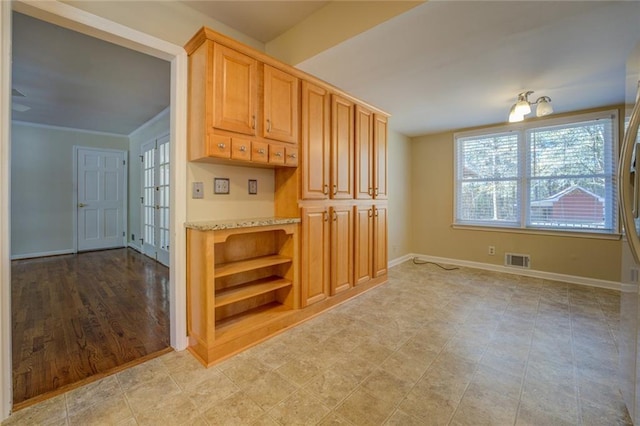 kitchen with crown molding, light brown cabinetry, light hardwood / wood-style floors, and a notable chandelier