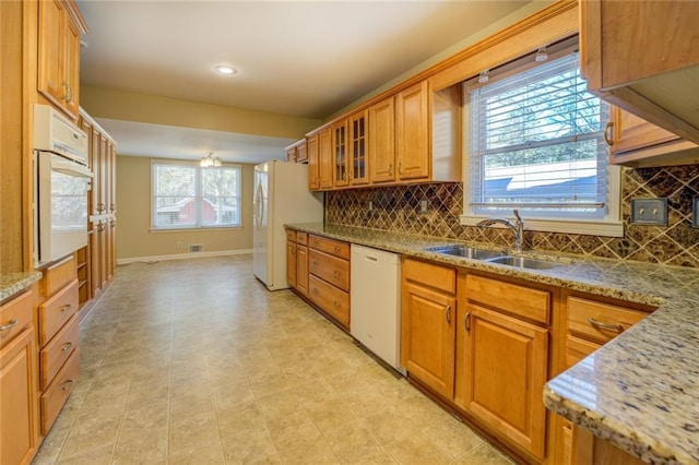 kitchen with white appliances, tasteful backsplash, a wealth of natural light, and sink