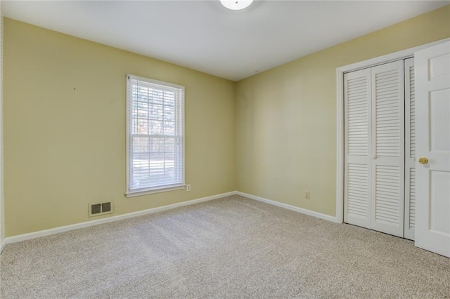 unfurnished bedroom featuring light carpet and a closet