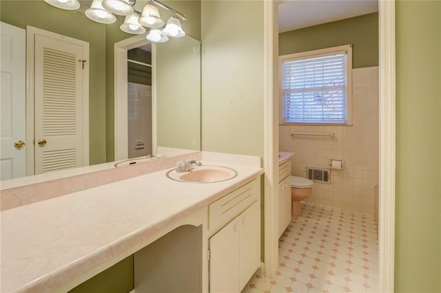 bathroom with vanity, toilet, and tile walls