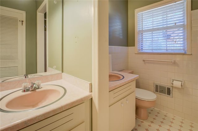 bathroom featuring vanity, tile walls, and toilet