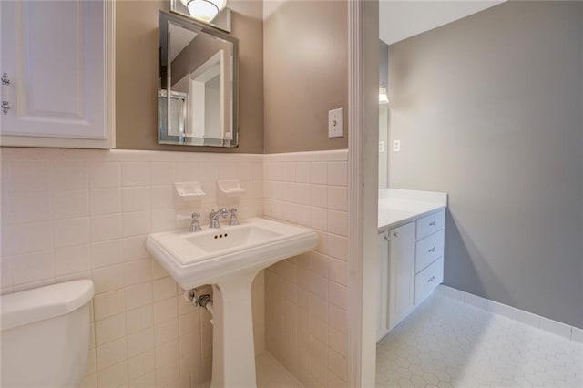 bathroom featuring tile patterned floors, toilet, and tile walls