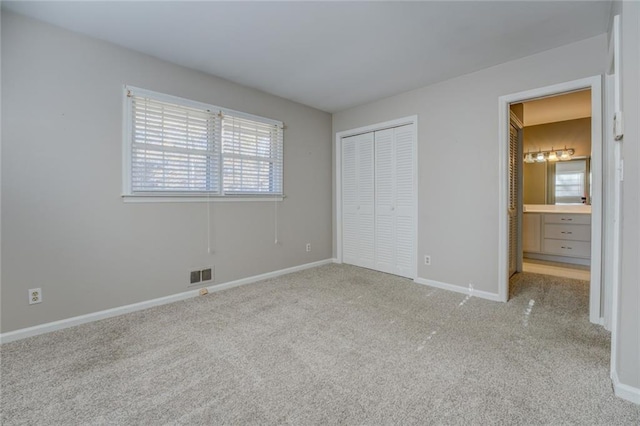 unfurnished bedroom with light colored carpet and connected bathroom