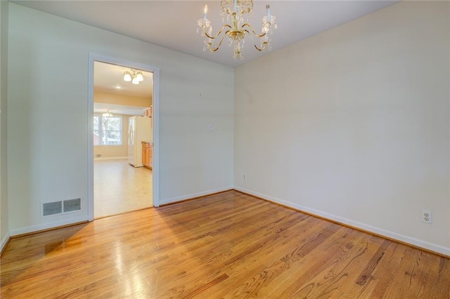 unfurnished room with light hardwood / wood-style floors and a chandelier