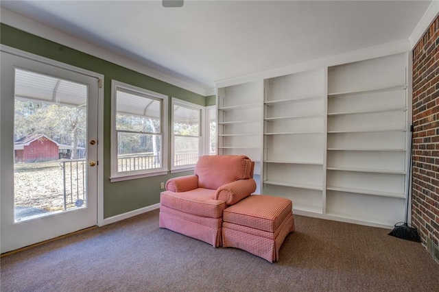 living area featuring built in shelves, carpet, and brick wall