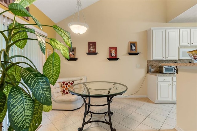 tiled dining area featuring high vaulted ceiling