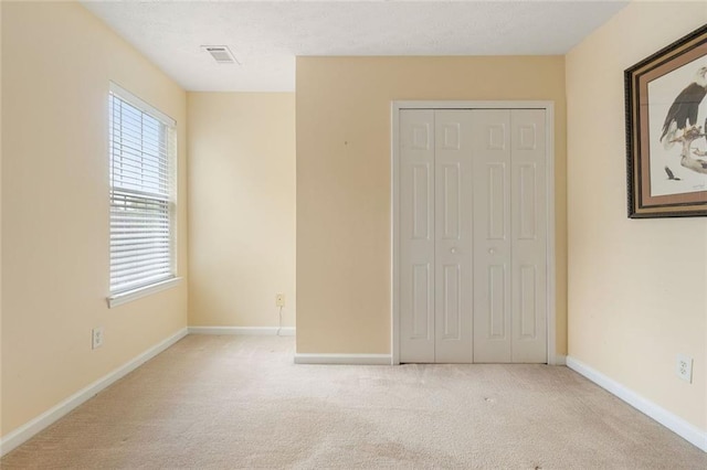 unfurnished bedroom with a closet and light colored carpet