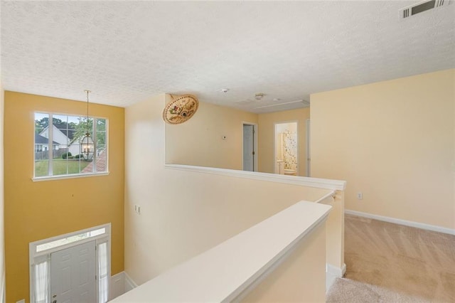 corridor featuring a textured ceiling and light colored carpet