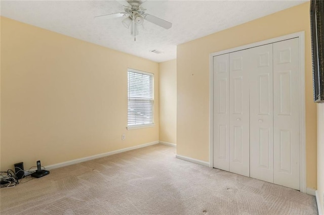 unfurnished bedroom with a closet, light carpet, and ceiling fan