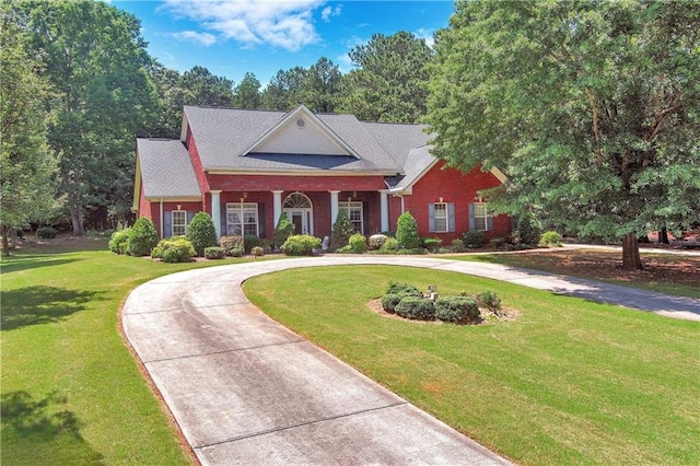 neoclassical / greek revival house with a front yard, brick siding, and curved driveway