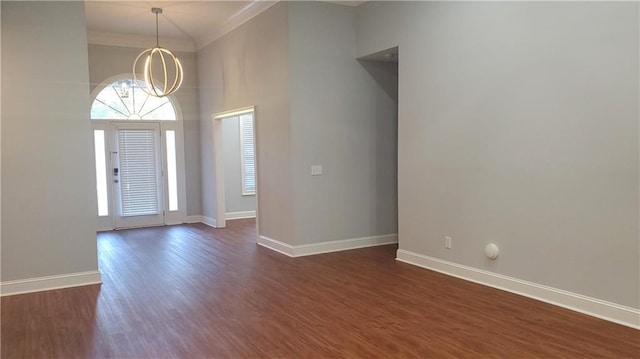 entrance foyer featuring dark wood-style floors, a high ceiling, a chandelier, crown molding, and baseboards