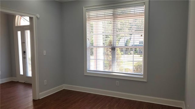 unfurnished room with dark wood-style flooring, baseboards, and plenty of natural light
