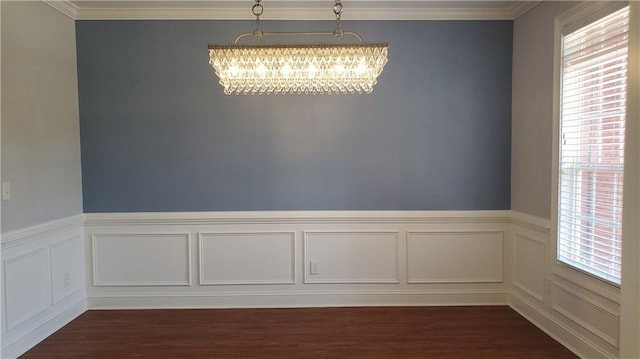 spare room with dark wood-style flooring, a chandelier, plenty of natural light, and a wainscoted wall