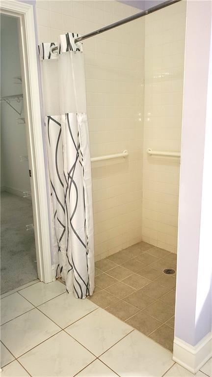bathroom with a tile shower and tile patterned flooring