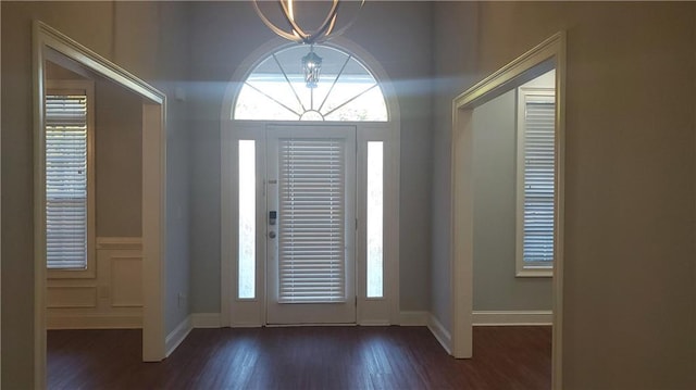 foyer entrance with an inviting chandelier, baseboards, and dark wood finished floors