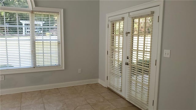 doorway with baseboards, light tile patterned floors, and french doors