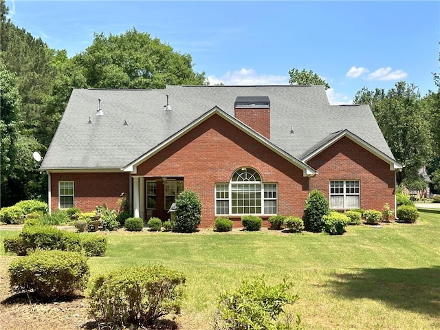 rear view of house with a lawn, a chimney, and brick siding