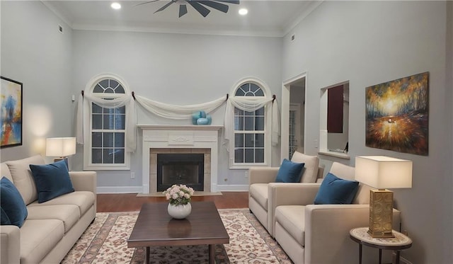 living room with recessed lighting, a tile fireplace, ornamental molding, a towering ceiling, and wood finished floors