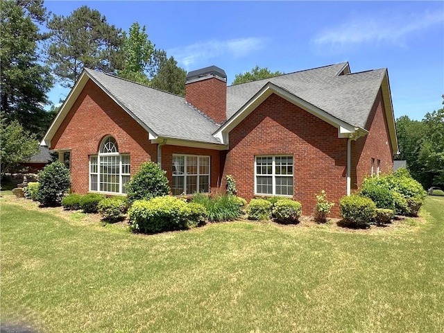 rear view of property with a lawn, a chimney, and brick siding