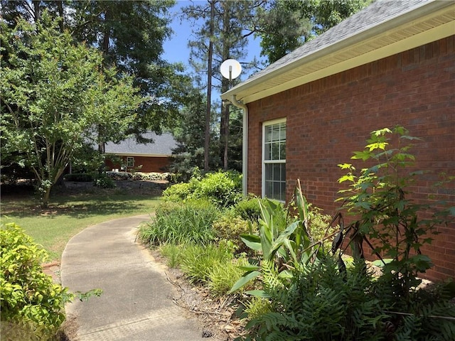 view of side of property featuring a shingled roof and brick siding