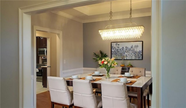 dining space with ornamental molding, a notable chandelier, and wood finished floors