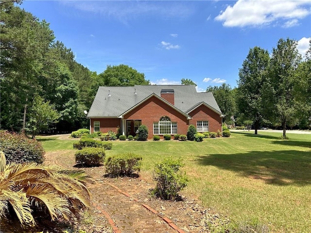 rear view of property featuring a chimney, brick siding, and a yard