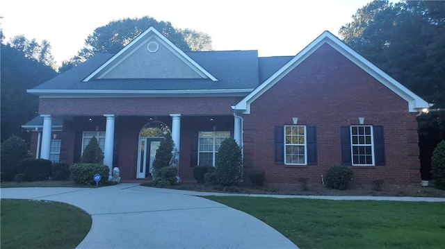 view of front facade with a front lawn, covered porch, and brick siding