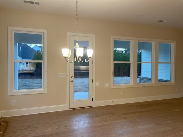 unfurnished dining area with dark wood-type flooring and a notable chandelier