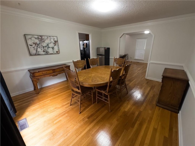 111 Bexley Ln, Douglasville, GA 30134 - dining area featuring light wood-style floors, arched walkways, a textured ceiling, and crown molding