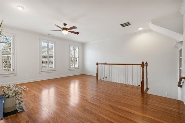 unfurnished room with ornamental molding, visible vents, baseboards, and wood finished floors