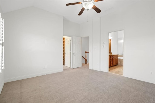 unfurnished bedroom with ensuite bathroom, light colored carpet, baseboards, a spacious closet, and a closet