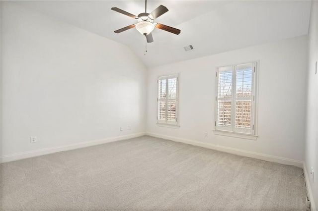 carpeted spare room with a ceiling fan, visible vents, vaulted ceiling, and baseboards