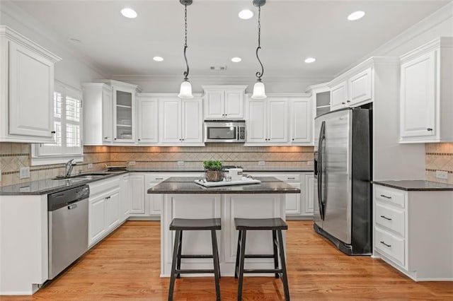 kitchen featuring a breakfast bar, a center island, stainless steel appliances, white cabinetry, and a sink