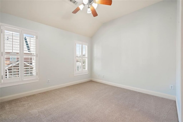 carpeted empty room with a ceiling fan, visible vents, vaulted ceiling, and baseboards