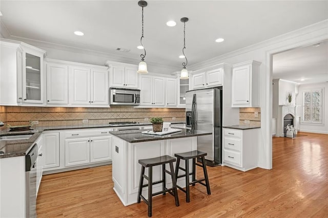 kitchen featuring stainless steel appliances, a center island, white cabinetry, and crown molding