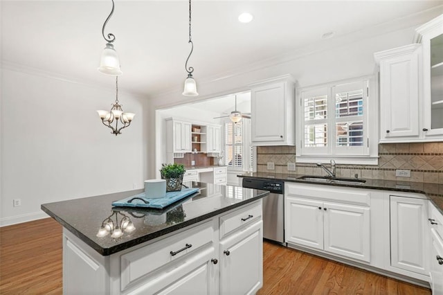 kitchen with a sink, light wood finished floors, decorative backsplash, and stainless steel dishwasher