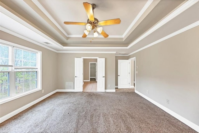 spare room with crown molding, light colored carpet, a tray ceiling, and ceiling fan