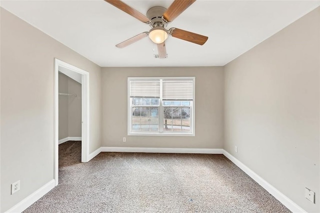 unfurnished bedroom with a closet, carpet floors, ceiling fan, and a spacious closet