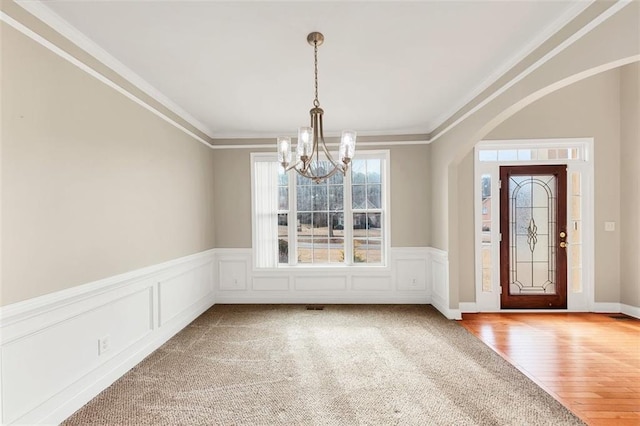 entrance foyer with an inviting chandelier, ornamental molding, and hardwood / wood-style floors