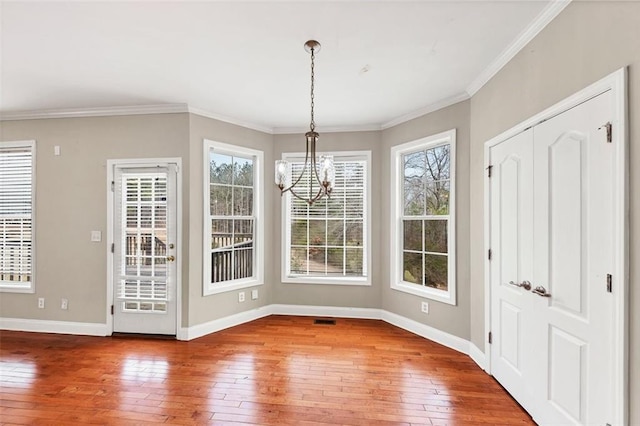 unfurnished dining area featuring hardwood / wood-style flooring, ornamental molding, and a chandelier