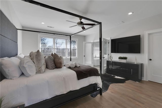 bedroom with wood-type flooring, ceiling fan, and ensuite bath