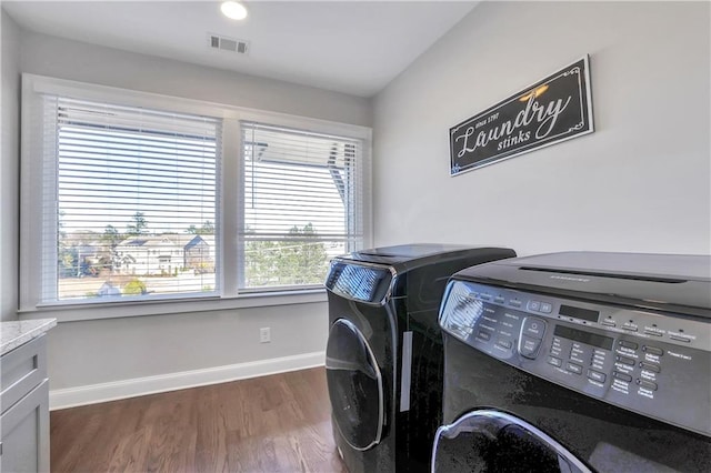 clothes washing area with independent washer and dryer, dark hardwood / wood-style floors, and cabinets