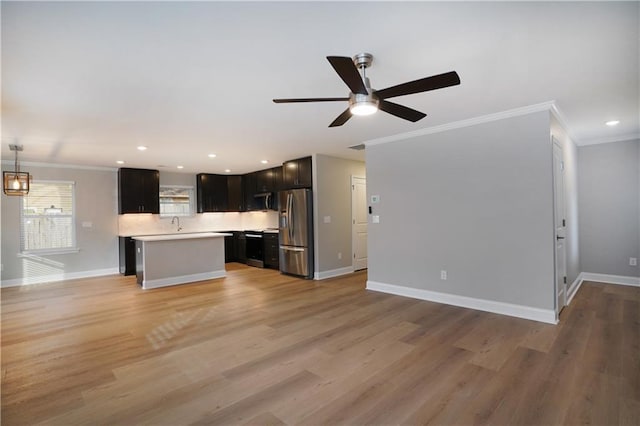 unfurnished living room featuring crown molding, sink, ceiling fan, and light hardwood / wood-style floors