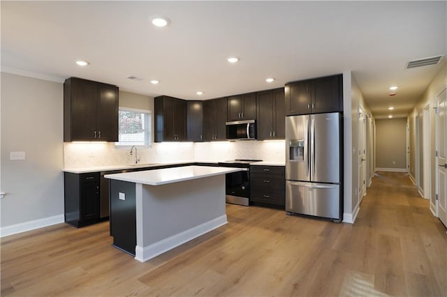 kitchen with tasteful backsplash, stainless steel appliances, a center island, and light hardwood / wood-style floors