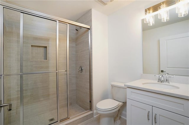 bathroom featuring vanity, a shower with shower door, and toilet